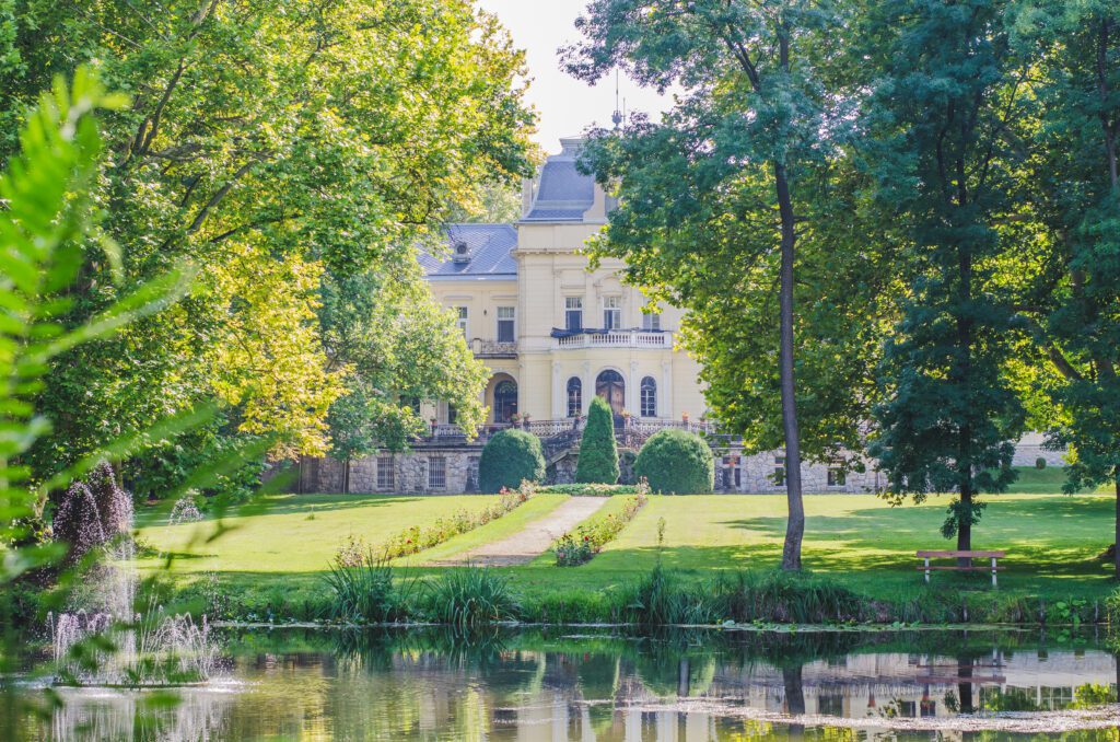 A beautiful landscape with a pond, a green lawn, and a castle in the background.