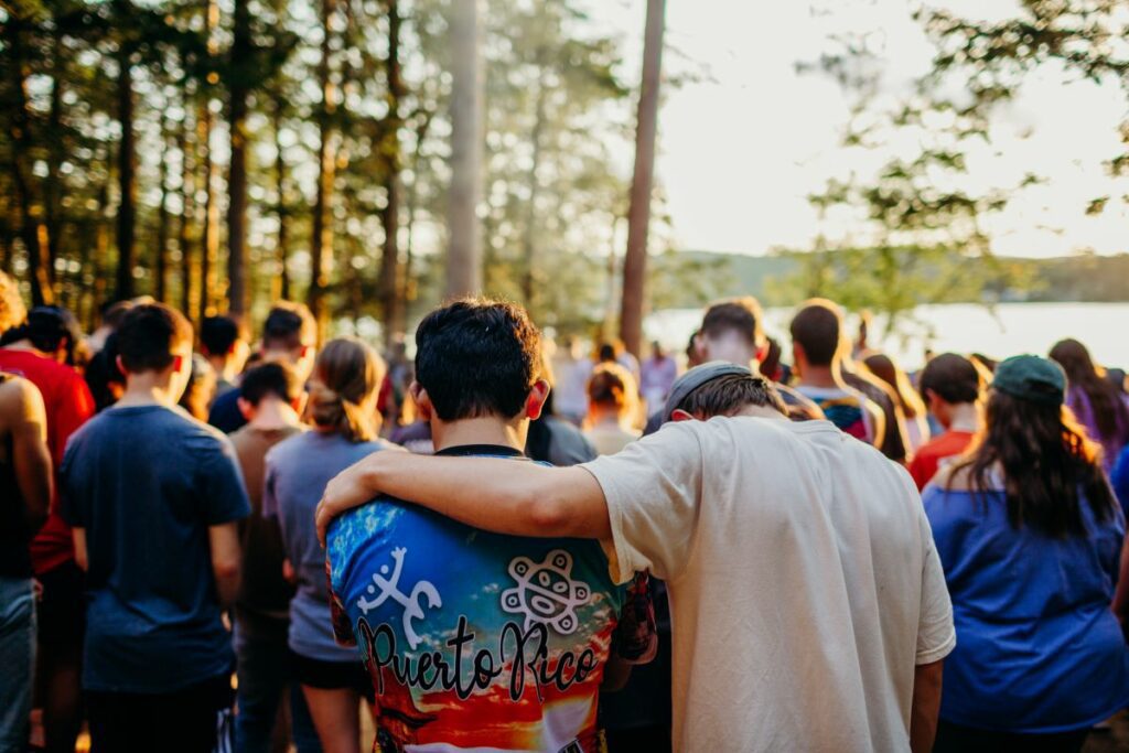 A crowd of students at an outdoor youth camp with their heads bowed in prayer. Photo by Word of Life on Flickr.